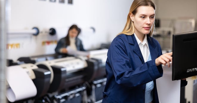 Woman working in publishing facility, using printer, pushing buttons on display.