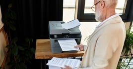 In a chic office, a senior businessman reviews printed documents, showcasing professionalism and elegance.