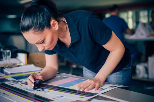woman using a loupe to spot check the color on a printed page