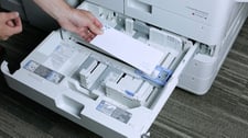 Hand putting envelopes in a printer
