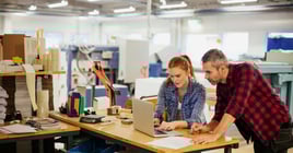 Diverse group of coworkers using a laptop in a printing press office