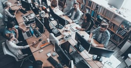 Confident business experts a work. Top view of group of young business people in smart casual wear working together while sitting at the large office desk