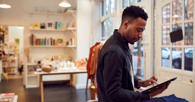 Male Small Business Owner Checks Stock In Shop Using Digital Tablet