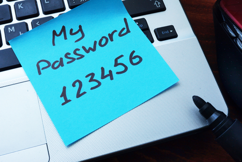 post it note on a laptop with a password written on it
