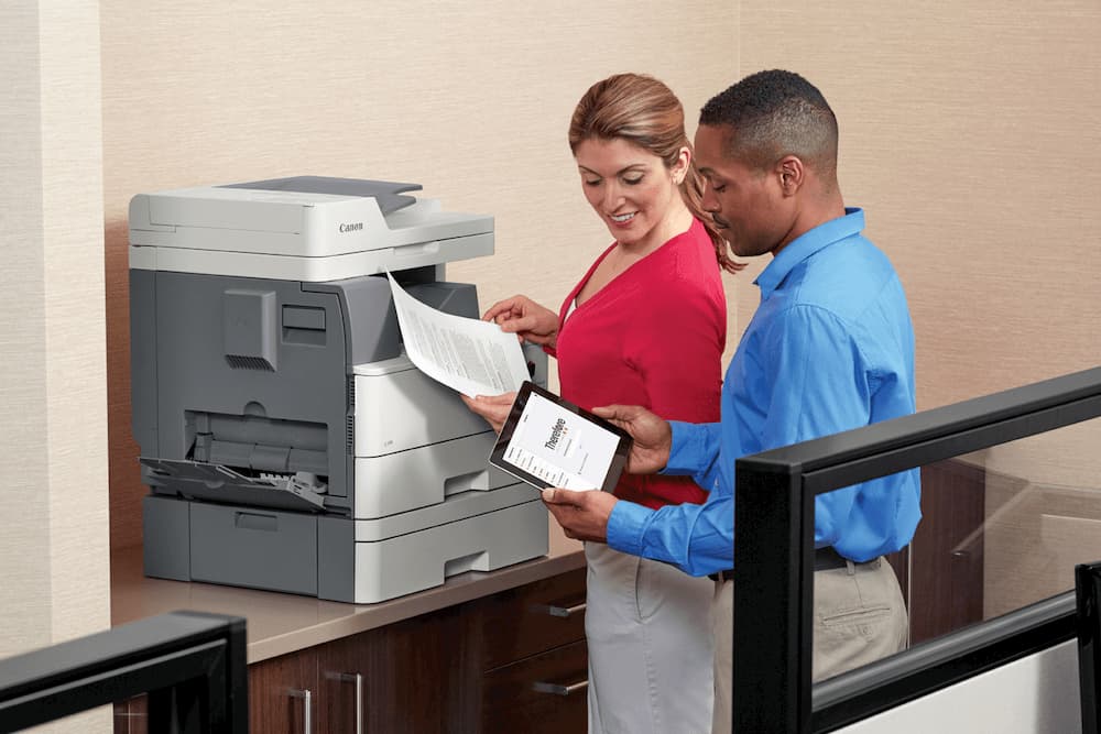 two coworkers getting documents off a workplace printer 