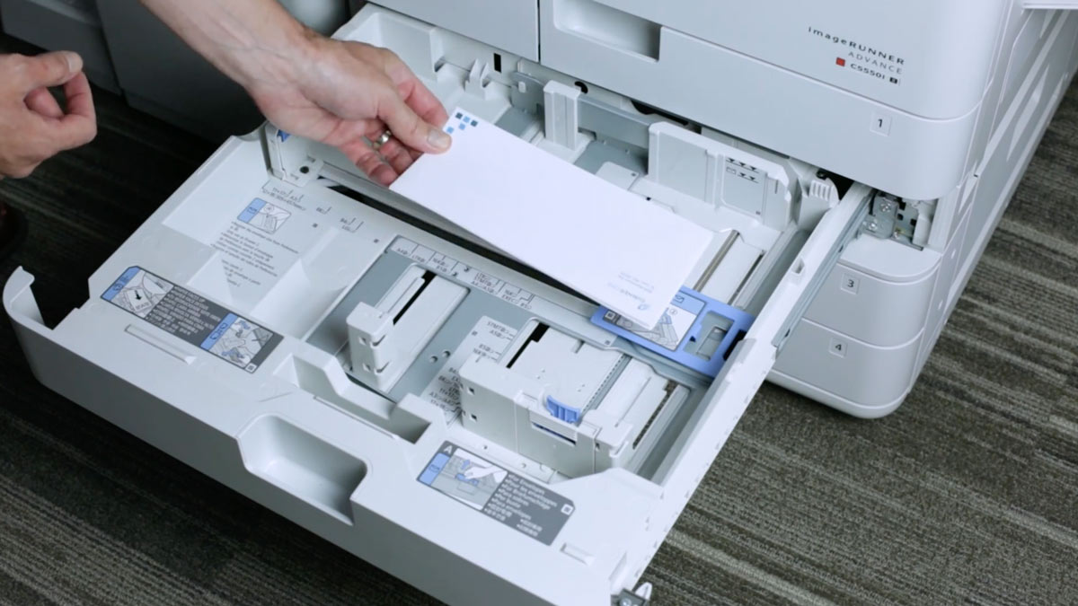 Hand putting envelopes in a printer
