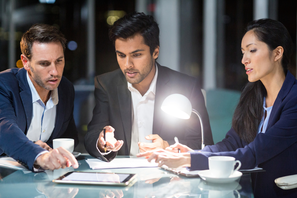 Group of businesspeople discussing over digital tablet in the office