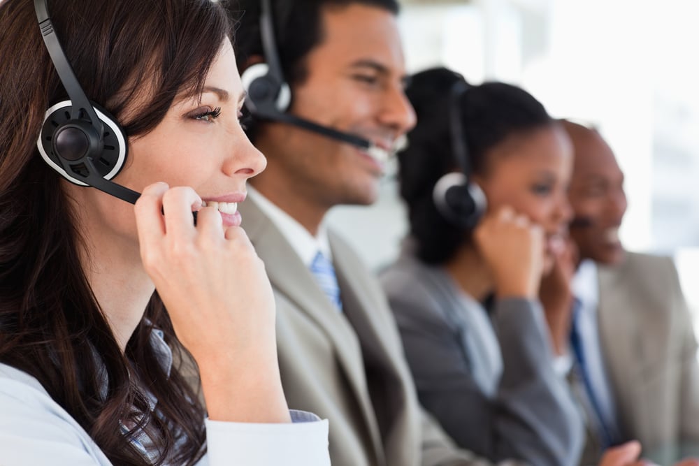 Young-employee-working-with-a-headset-and-accompanied-by-her-team.jpg