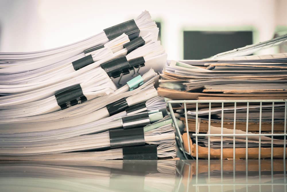 2 large stacks on paper on a desk 