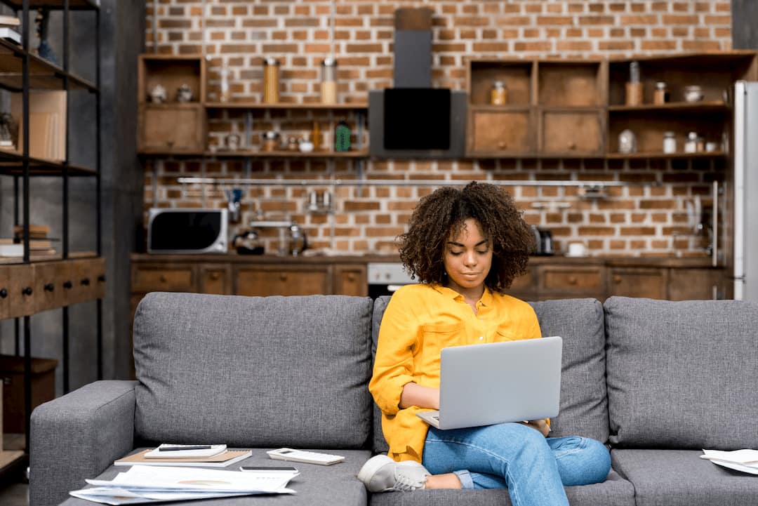 woman-working-from-home-on-a-laptop-wth-a-stack-of-papers